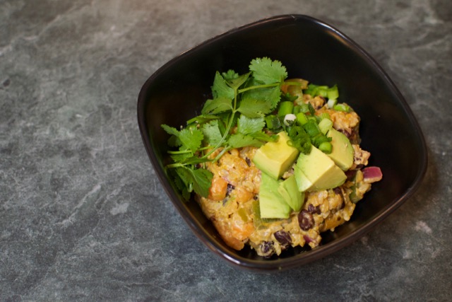 Spicy bean and rice bowl topped with avocado, cilantro, and green onions.
